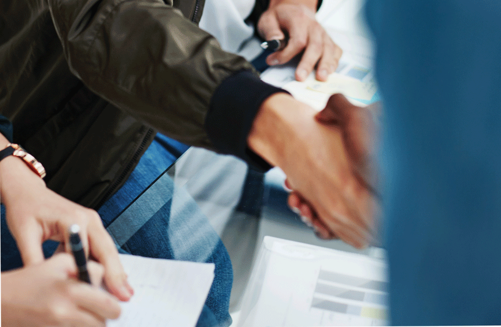 Close up of two people shaking hands over a table, representing jobs for people with epilepsy.