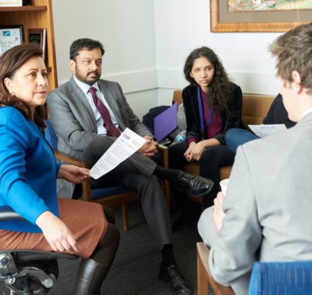 A group of people sit and talk in a legislator's office.