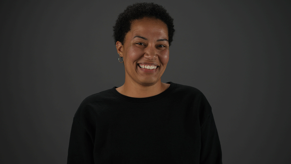 Portrait of a woman with short hair smiling at the camera against a dark backdrop.
