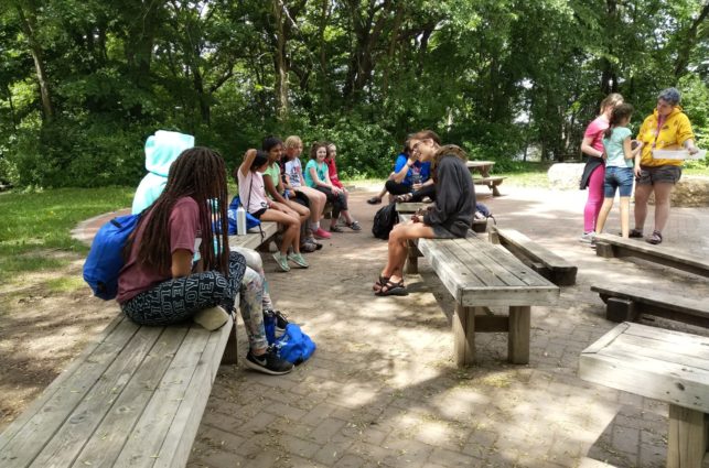 Campers sit together on wooden benches