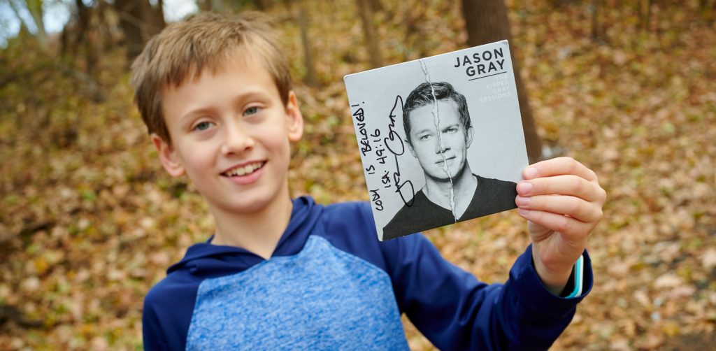 9 year old boy outside holding Jason Gray music CD