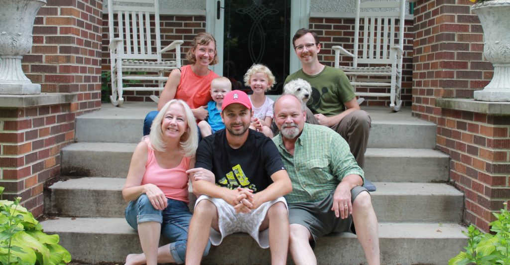 family of 7 sit on front steps of house