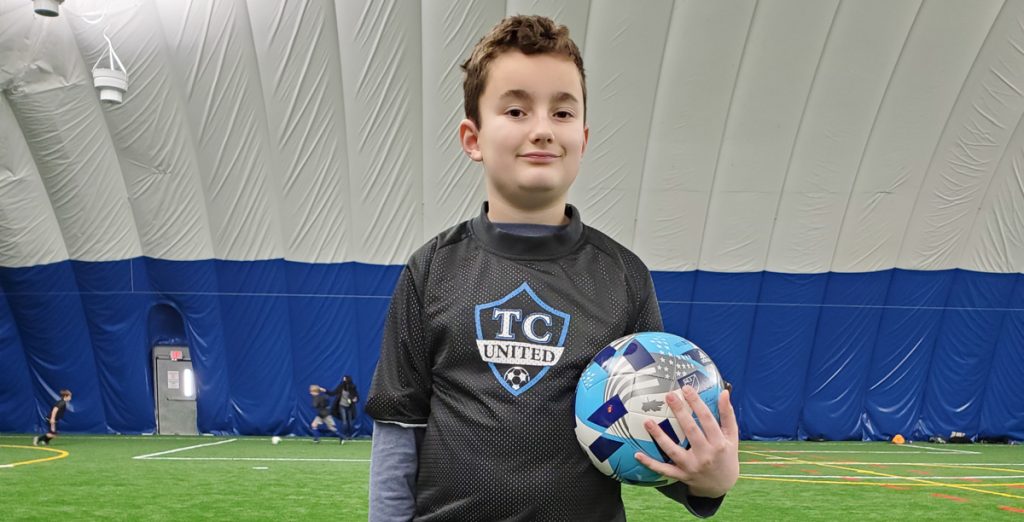 young boy holding soccer ball in arena