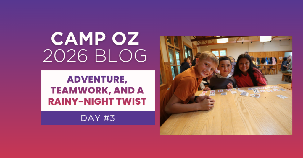 Three campers gathered around a wooden table playing a card game inside a camp lodge, with other campers in the background; graphic text reads “Camp Oz 2026 Blog – Day #3: Adventure, Teamwork, and a Rainy-Night Twist